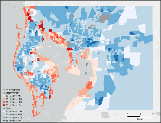 A map of Hillsborough and Pinellas Counties in the Tampa Bay region is shown. Water is light gray. Land is broken into block groups and colors indicate the percentage of residents that will not evacuate and instead remain home during the storm. Orange to red colors show an increasing likelihood of not evacuating in areas with a mandatory evacuation order. Light to dark blue colors show an increasing likelihood of not evacuating in areas that do not have a mandatory evacuation order.