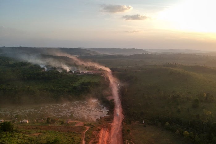 An aerial view of red dust from a highway mixes with smoke from fires at sunset in an agriculture town in northern Brazil on September 6, 2019.